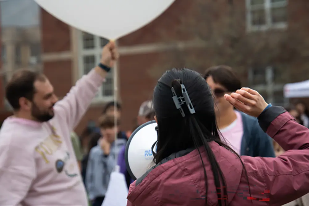 A student ready to launch a weather balloon as another talks into a megaphone.